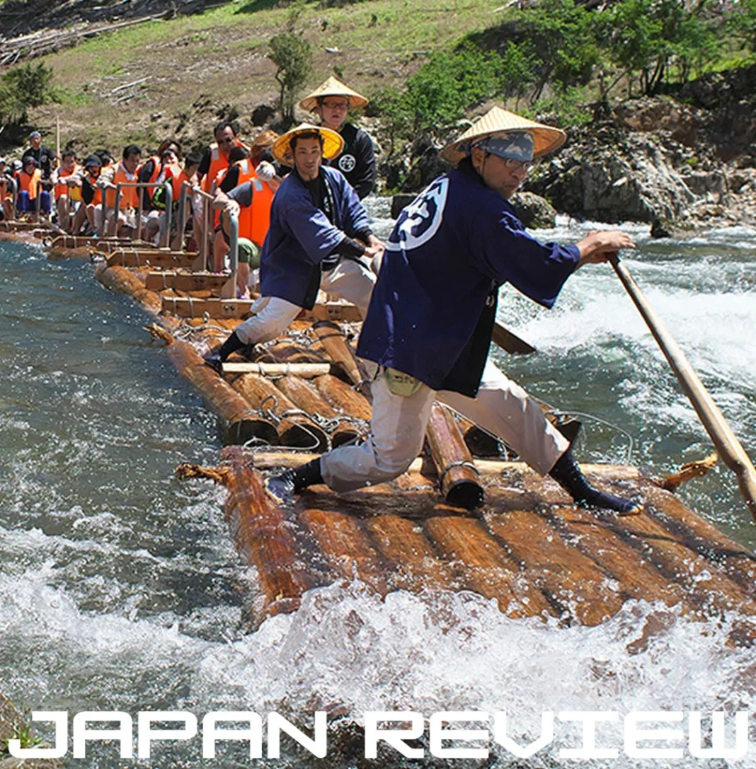 Turistas descem corredeiras do rio Kitayama em jangada tradicional cercada por montanhas e florestas japonesas.
