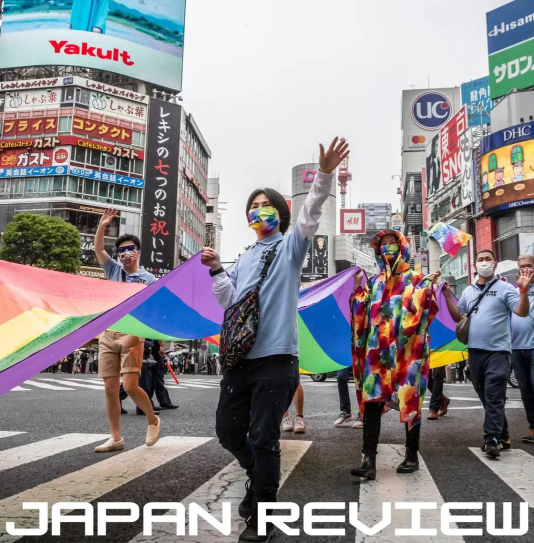 Participantes de evento LGBTQIA+ no Japão exibem bandeiras coloridas durante manifestação pela diversidade e inclusão.